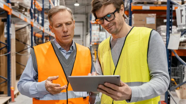 Maturidade digital B2B: dois profissionais em ambiente fabril observando um tablet.